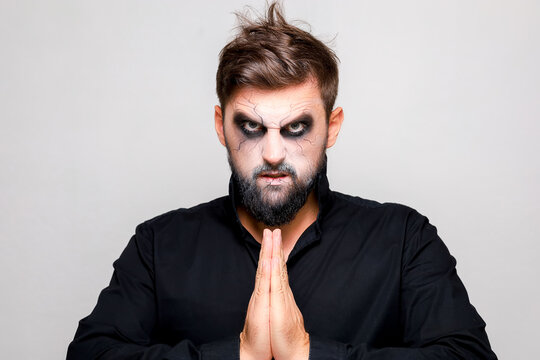 Scary undead-style makeup for Halloween on a bearded man who shows gestures