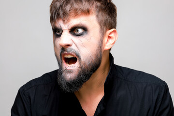 Portrait of a man with a beard and a menacing look with undead-style makeup on All Saints' Day on October 31