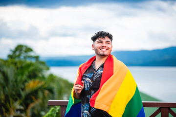 Hombre gay con la bandera de la diversidad en sus hombros en exterior