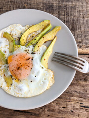 fried egg with avocado slices on the table for breakfast