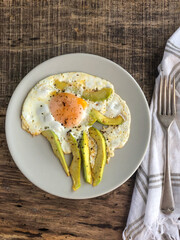 fried egg with avocado slices on the table for breakfast