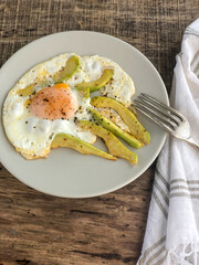 fried egg with avocado slices on the table for breakfast