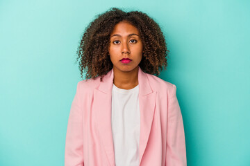 Fototapeta premium Young african american woman with curly hair isolated on blue background sad, serious face, feeling miserable and displeased.