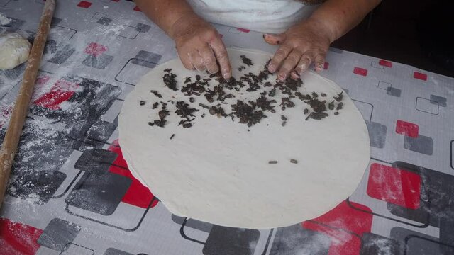 Lady stuffing "gozleme" dough with herbs. Gozleme is a traditional stuffed Turkish flat bread