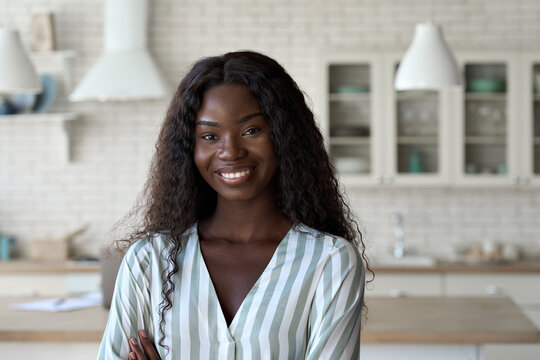 Young happy cheerful gorgeous African American black girl student in smart casual clothing with perfect smile posing indoors at modern kitchen home office looking at camera. Headshot portrait.