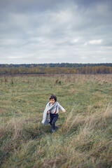 Naklejka na ściany i meble boy child in plaid pants, hat, suspenders and scarf stands in a field
