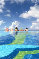 young women having fun in hotel infinity pool in Caribbean sea. Concept of vacation and bachelorette pool party