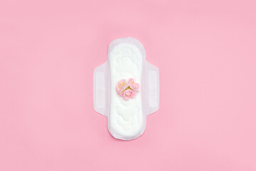 Feminine sanitary napkin with pink flowers. First menstruation concept. Copy space. - obrazy, fototapety, plakaty