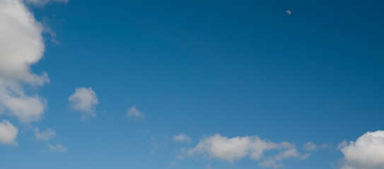 Naklejka na ściany i meble Panoramic sky background. Moon and clouds in blue sky