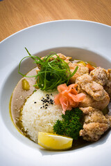 Japanese food - Detail, Curry Karaage Don with white rice, curry, hard boiled egg, salad and miso soup over a wooden table.