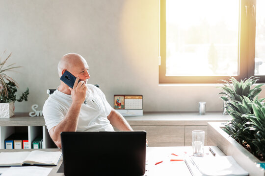 Middle aged business man talking on the phone in the office. Casual work wear.