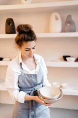 A woman works in a pottery workshop. The master makes dishes from ceramics. A uniformed employee in a decorative products studio.