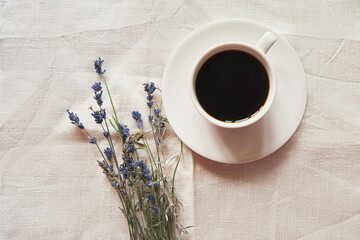 Coffee in a white cup on white linen fabric. Positive morning with coffee and lavender