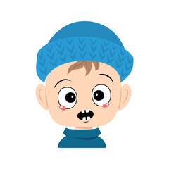 Boy with emotions panic, surprised face, shocked eyes in blue knitted hat. Cute kid with scared expression in autumnal or winter headdress. Head of adorable toddler