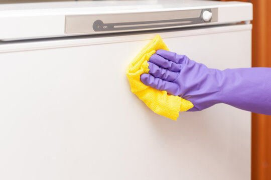 Woman's Hand Wipes The White Refrigerator Door