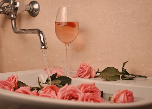 Glass of wine and bouquet of pink roses in sink