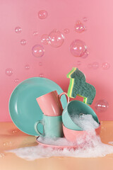 creative still life in bright colors with a sponge in the shape of a unicorn. The unicorn will say through the mountains of dirty dishes filled with foam for washing dishes surrounded by soap bubbles