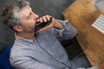 Un homme d'âge mûr 50 ans est en train de travailler au bureau, il téléphone devant son...