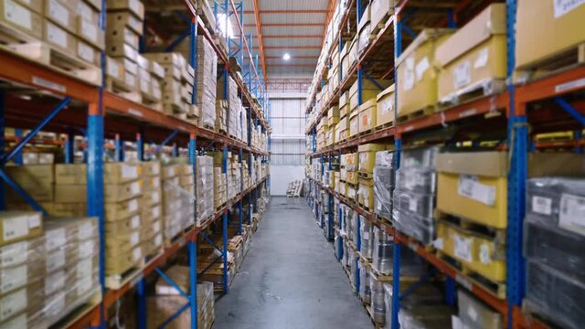 Footage of a large distribution warehouse with many cardboard boxes on the shelf. Packaged products are ready for delivery