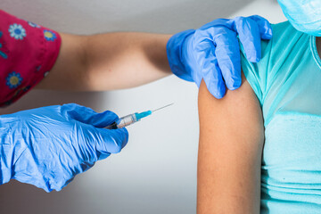 children's nurse injecting arm of little brown girl, doctor's hands with rubber gloves injecting covid-19 or flu vaccine. medical, health and pandemic concept