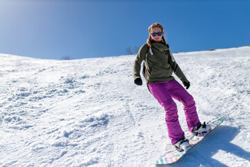 Focused young Caucasian woman snowboarding on empty tracks of Jahorina ski resort on a beautiful...