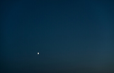 A crescent moon in the night sky in complete darkness