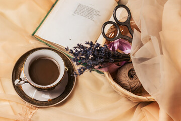 The atmosphere of a romantic morning, coffee in bed. A cup of coffee, an open book and a bouquet of lavender on a silk bed in French style. Home interior. Lifestyle. 