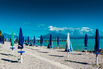 Sirmione, Italy - September 22, 2021: Closed umbrellas on the beach of Lake Garda.