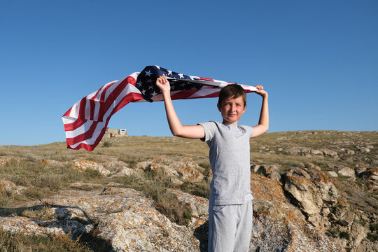 A boy holding waving US flag, beeng a patriot concept