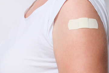 A woman showing her arm with an adhesive bandage after injection of vaccine close up. Getting vaccinated from corona virus, covid-19