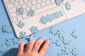 Puzzle elements in a chain of several blocks on a laptop keyboard, software development, concept. Mosaic on a blue background