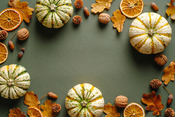 Autumn flat lay composition with pumpkins, dry oranges, acorns, oak leaves on green background....