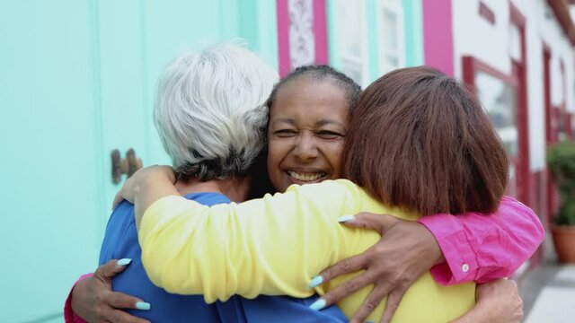 Multiracial senior women having fun together hugging outdoor in the city - Real people, elderly friendship concept