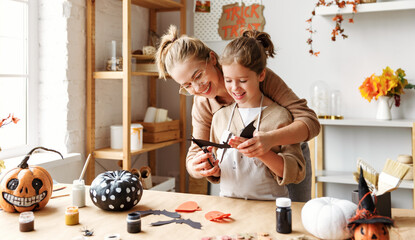 Happy smiling family mother and daughter making Halloween home decorations together