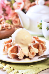 Plate of belgian waffles with ice cream on wooden table