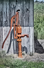 old rusted water pump in front of weathered wood wall