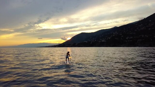 Aerial drone view passing a silhouette sup boarder, sunset in Golfo paradiso, Italy