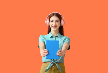 Young woman with headphones and book on color background