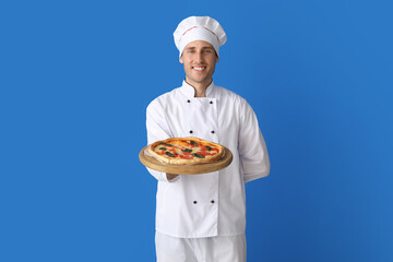 Handsome chef with delicious pizza on blue background