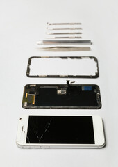 Disassembled mobile phone and technician tools on light background