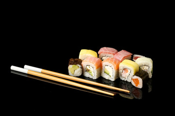 Set of different sushi rolls and chopsticks on dark background