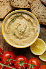 Bowl with tasty baba ghanoush, bread, lemon and tomato on table, closeup