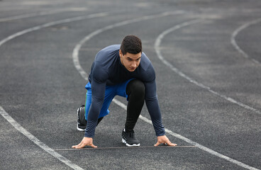 Muscular young man getting ready to run at stadium