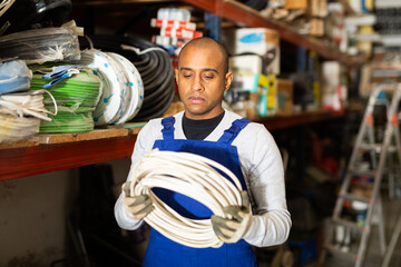 Fototapeta premium Confident latin american handyman man choosing materials for overhauls in building materials store