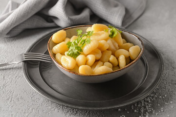 Bowl with tasty gnocchi on light background