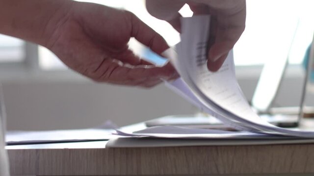 Businessman hand flipping pages of document paper in the office desk