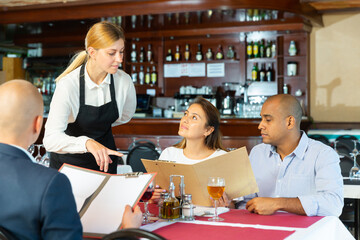 Polite waitress offers to choose a dish from the menu