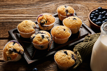 Board with tasty blueberry muffins on wooden background
