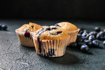Tasty blueberry muffins and berries on dark background
