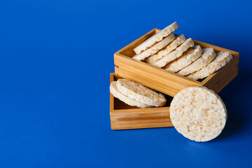 Wooden boxes with crispy rice crackers on color background